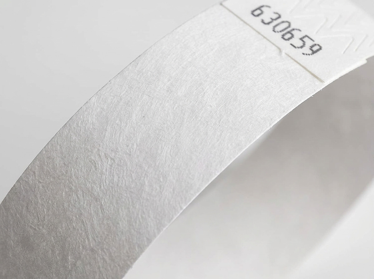 Gros plan sur la surface non-tissée d'un bracelet Tyvek blanc, montrant la texture caractéristique du polyéthylène haute densité